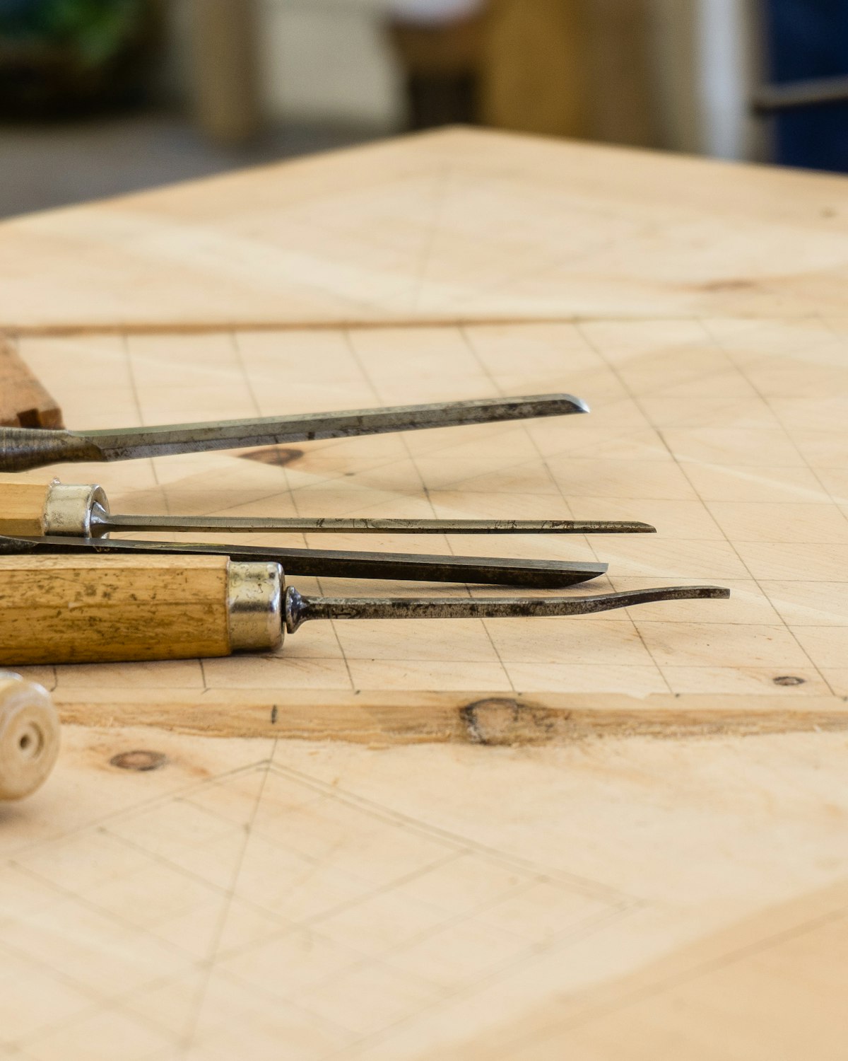 Gubias y herramientas de carpintería sobre un banco de madera con líneas de trazado dibujadas a lápiz