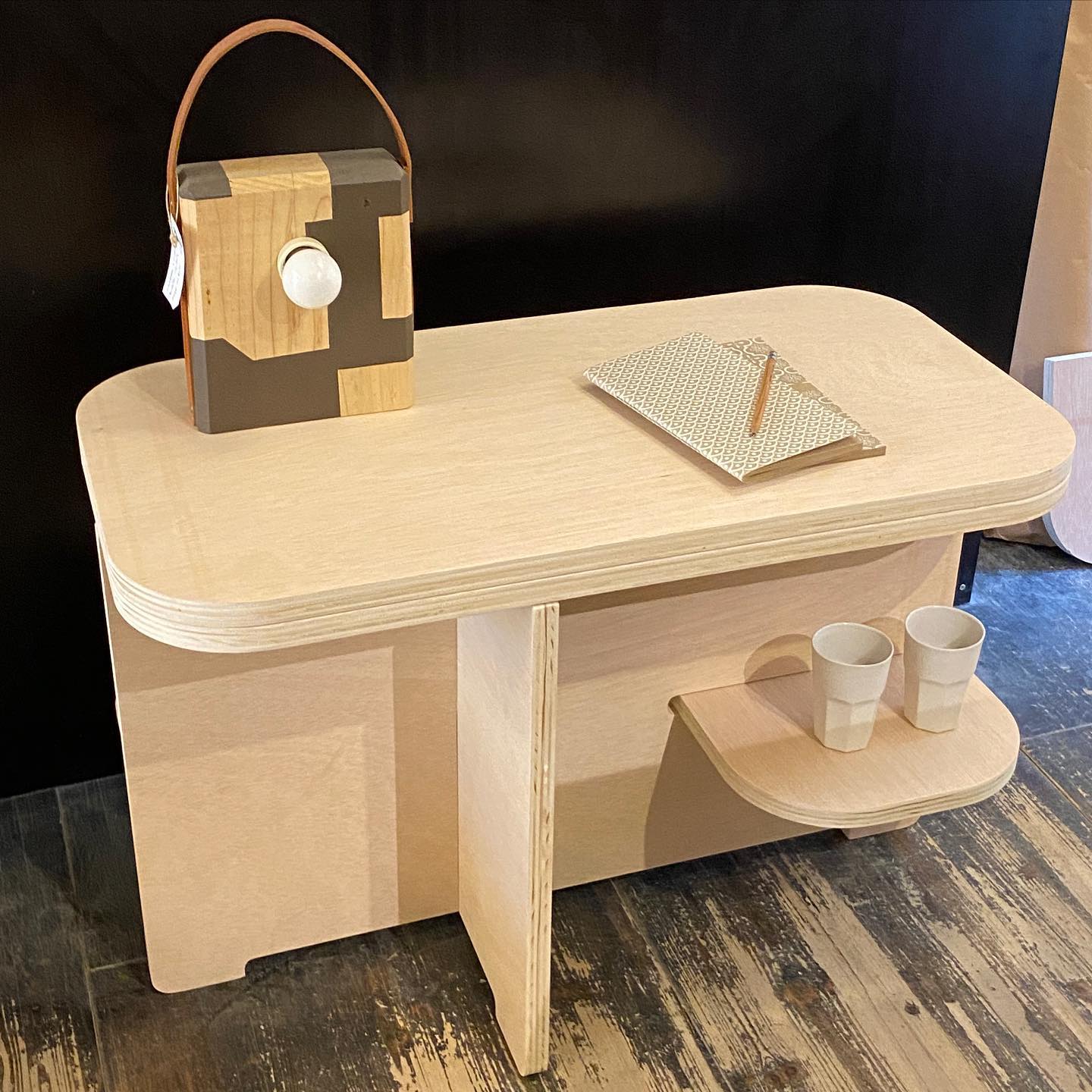 Escritorio de madera de caballete con silla de contrachapado curvado bajo luz de ventana